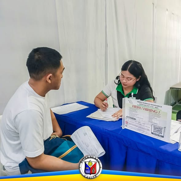 Mga aplikante na kinakausap ng kawani ng HR sa recruitment booth sa Sabang, Naic