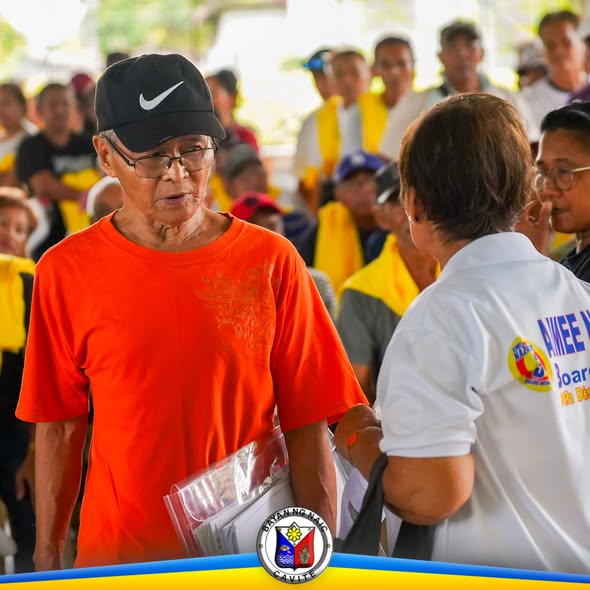 Matandang lalaki na may hawak na folder habang kausap ang isang staff sa pamamahagi ng social pension