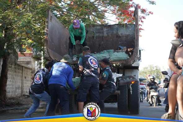 Mga tauhan at boluntaryo na naglo-load ng basura sa dump truck sa clean-up drive sa Ciudad Nuevo Phase 3