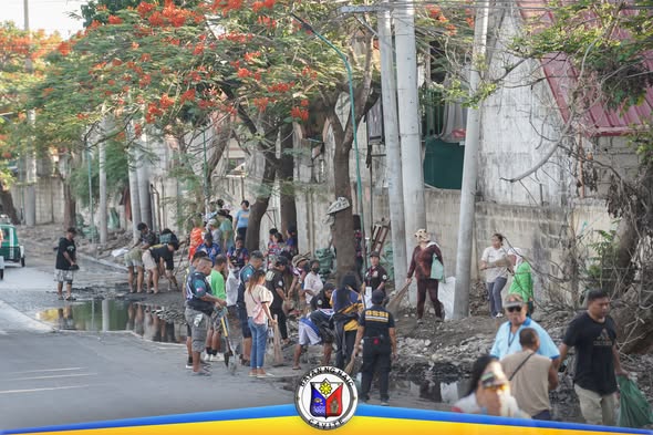 Mga residente at tauhan na naglilinis ng kalsada sa Ciudad Nuevo Phase 3 habang may nagwawalis at nagdadala ng basura