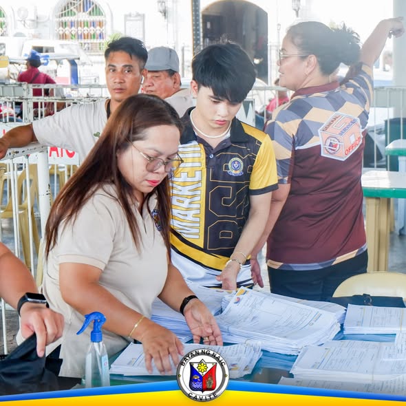 Mga kawani ng MSWDO na nag-aayos ng mga dokumento para sa burial assistance sa Naic Town Plaza