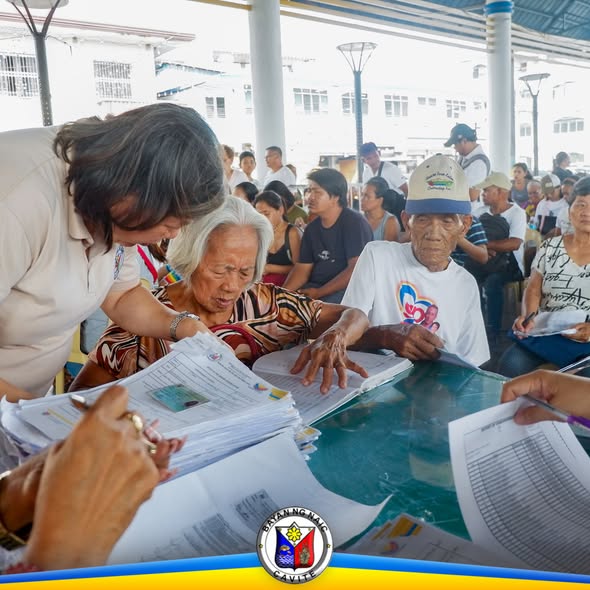 Mga matatanda at kawani habang nag-aasikaso ng mga papeles sa burial assistance sa Naic Town Plaza