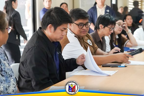 Pulong ng MDRRMO sa ABC Hall, Naic, kung saan sinusuri ng mga kalahok ang mga papeles sa mesa