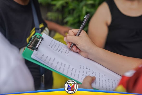 Kamay na nagsusulat sa listahan sa clipboard habang namamahagi ng gamot kontra leptospirosis sa Sapa