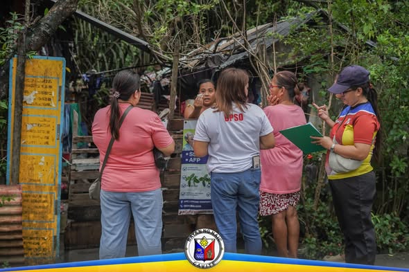 Mga kawani ng MHO at BHW na nag-uusap sa labas ng bahay sa Barangay Sapa habang nagbibigay ng gamot kontra leptospirosis