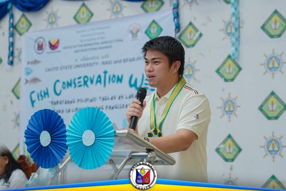 Poster: Fish Conservation Week, CvSU Naic. Lalaki na nagsasalita sa mikropono sa entablado ng FASD Day