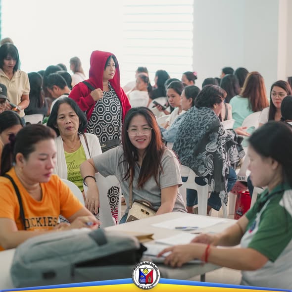 Mga dumalo na nakaupo sa mesa habang nagpoproseso ng papeles sa loob ng hall sa Triple 8 Building, Sabang, Naic