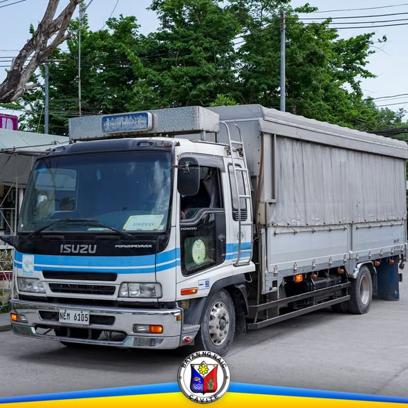 Trak ng Isuzu na may takip na kanbas, nakaparada sa kalsada, ginamit sa pagdadala ng school supplies sa Naic