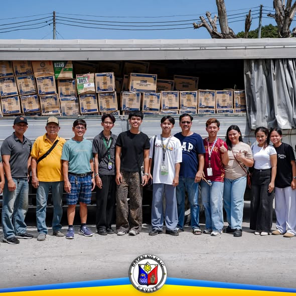Grupo ng mga tao sa harap ng trak na puno ng kahon ng school supplies para sa Naic Integrated National High School