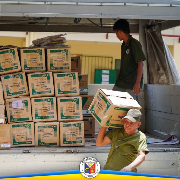 Mga kawani na nagbubuhat ng mga kahon ng school supplies mula sa trak sa Naic