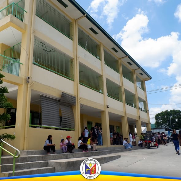 Mga tao sa harap ng gusali ng paaralan habang may pamamahagi ng school supplies sa Naic