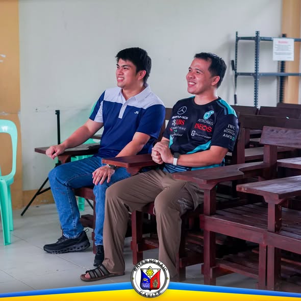 Dalawang lalaking nakaupo sa mga bagong gawang upuan sa silid-aralan sa Naic