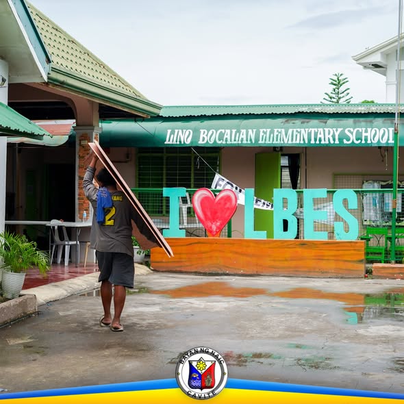 Lalaking nagdadala ng kahoy sa harap ng Lino Bocalan Elementary School habang inihahanda ang paaralan sa pasukan