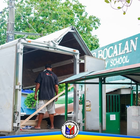 Litrato: Lalaking nagkakarga ng mga kahoy sa trak sa harap ng Lino Bocalan Elementary School
