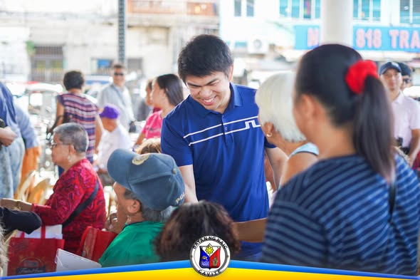 Mga senior citizen sa Naic Town Plaza habang tinutulungan ng isang opisyal sa National Social Pension Program
