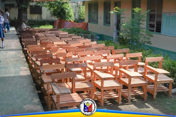Mga bagong upuang kahoy para sa paaralan na nakahanay sa gilid ng gusali ng Muzon Elementary School