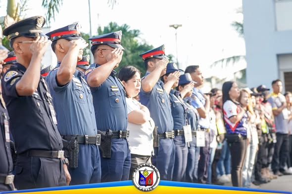 Mga uniporme na tauhan na nagsasaludo habang may flag raising ceremony sa labas ng Naic Municipal Hall