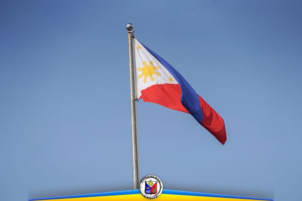 Watawat ng Pilipinas na kumakaway sa poste laban sa asul na kalangitan, sa Flag Raising Ceremony ng Naic