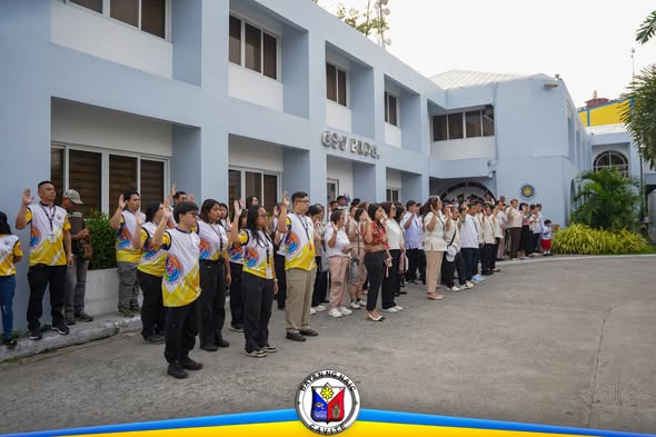 Mga kawani habang nagtataas ng kamay sa flag raising ceremony sa harap ng gusali ng LGU Naic