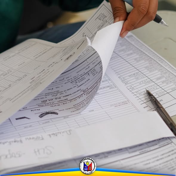Kamay na nagbubuklat ng mga papel ng rehistrasyon ng livestock at poultry farmers sa mesa