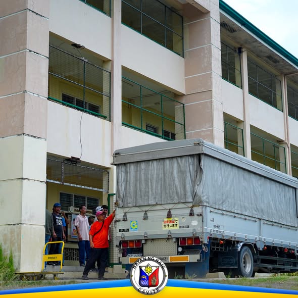 Mga tauhan na naglo-load ng school supplies sa truck sa harap ng paaralan sa Naic