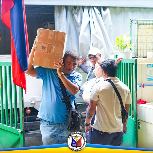 Mga tauhan na nagbubuhat ng kahon ng school supplies sa gate ng paaralan sa Naic