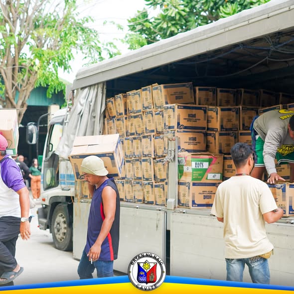 Mga lalaking nagbubuhat ng mga kahon mula sa trak para sa pamamahagi ng school supplies sa Naic