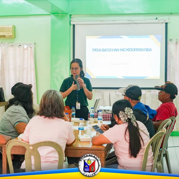 Babaeng nagsasalita sa harap ng mga kalahok sa seminar ng kooperatiba; may screen na may pamagat na Mga Batayan ng…