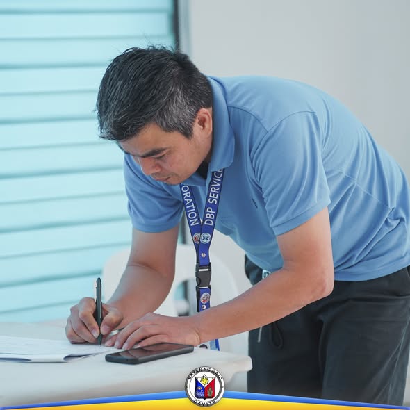 Isang lalaking nagsusulat sa dokumento sa mesa habang nasa pagpupulong sa Naic