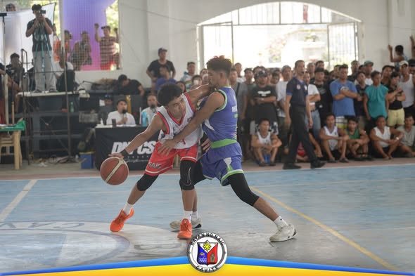 Mga manlalaro ng basketball na nag-aagawan ng bola sa loob ng court habang nanonood ang mga tao sa bleachers