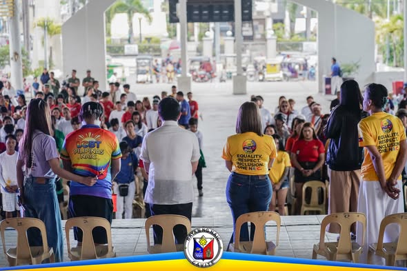 Mga tao sa Naic Town Plaza habang nakikiisa sa Pride Month Celebration, may suot na makukulay at dilaw na shirt