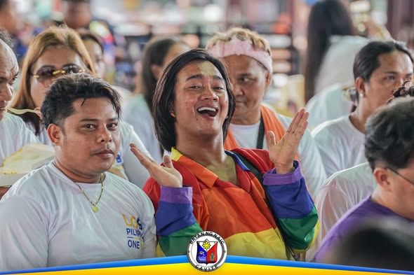Masayang tao na nakasuot ng rainbow na jacket sa Pride Month Celebration sa Naic Town Plaza