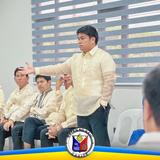 Lalaking naka-barong na nagsasalita habang nakikinig ang mga kalalakihan sa pulong sa Naic