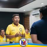Mga tao sa pulong habang nagsasalita ang lalaking naka-dilaw na polo sa loob ng opisina sa Naic
