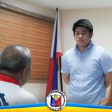 Pulong sa opisina ng Naic habang nag-uusap ang dalawang lalaki sa harap ng watawat ng Pilipinas