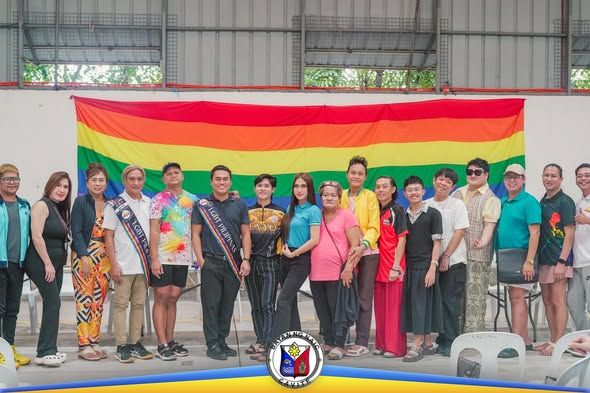 Grupo ng mga kasapi ng LGBT Pilipinas One Naic sa harap ng rainbow flag matapos ang pagpupulong at halalan