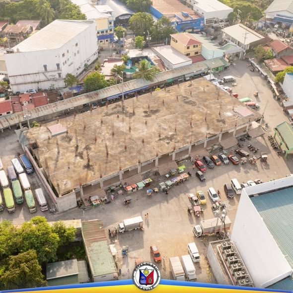 Litrato mula sa itaas ng Naic Public Market na may mga tindahan, sasakyan, at bahagyang tapos na bubong