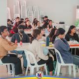 Mga kabataang dumalo sa peer facilitation training na nakaupo sa mesa sa loob ng hall sa Naic