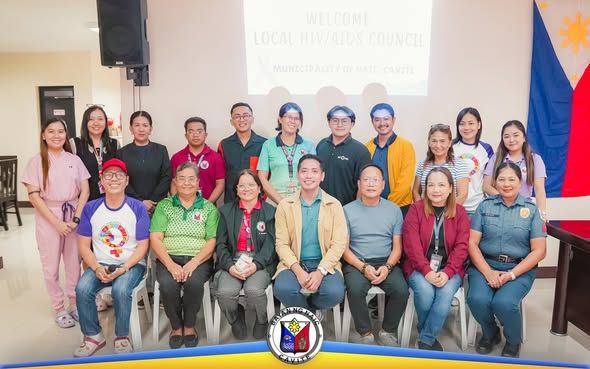 Grupo ng mga kalahok sa pulong ng Local AIDS Council sa Naic, Cavite, nagpose sa harap ng screen