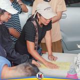Babaeng pumipirma ng yellow na form sa mesa habang nakapila ang mga tao sa PhilHealth caravan sa Naic
