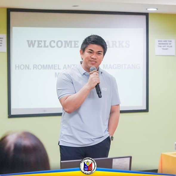 Isang opisyal na nagsasalita sa mikropono sa harap ng screen na may welcome remarks sa pagsasanay ng mga BNS