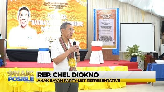 Tagapagsalita na may hawak na mikropono sa entablado ng Naic Youth Summit 2025, may caption ng broadcast sa ibaba.