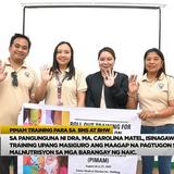 Mga kalahok at tagapagsanay ng PIMAM training na kumakaway habang may hawak na banner sa loob ng silid-pulungan