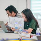 Mga kalahok sa Local Health Board Meeting na nagbabasa ng dokumento sa mesa, Sabang, Naic