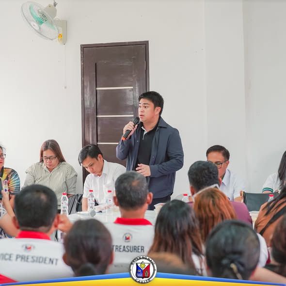 Nagsasalita sa mikropono ang isang opisyal habang nakikinig ang mga dumalo sa joint meeting sa Calubcob Daycare Center