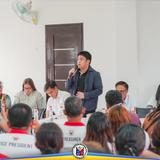 Nagsasalita sa mikropono ang isang opisyal habang nakikinig ang mga dumalo sa joint meeting sa Calubcob Daycare Center
