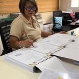 Isang babaeng pumipirma sa mga dokumento ng AIP sa opisina ng Naic