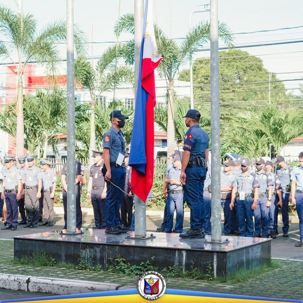 Mga uniporme na kawani habang itinataas ang watawat sa flag-raising ceremony sa Naic Municipal Hall