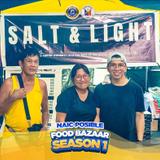 Tatlong tao sa harap ng food stall na may banner na "SALT & LIGHT" sa Naic Posible Food Bazaar