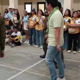 Isang lalaking naka-polong berde habang naglalakad sa court, pinanonood ng mga estudyante sa Sport Fest ng CvSU Naic